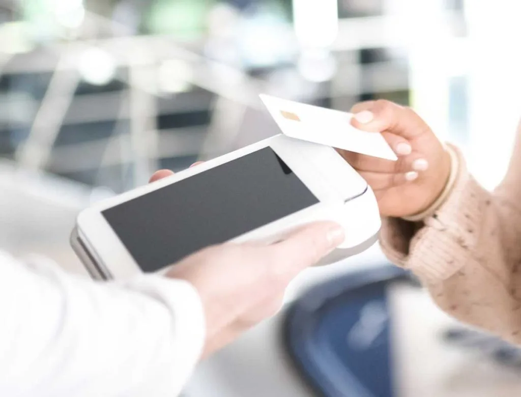 A customer makes a contactless card payment using a modern Online POS and Merchant Services terminal for quick and secure transactions.