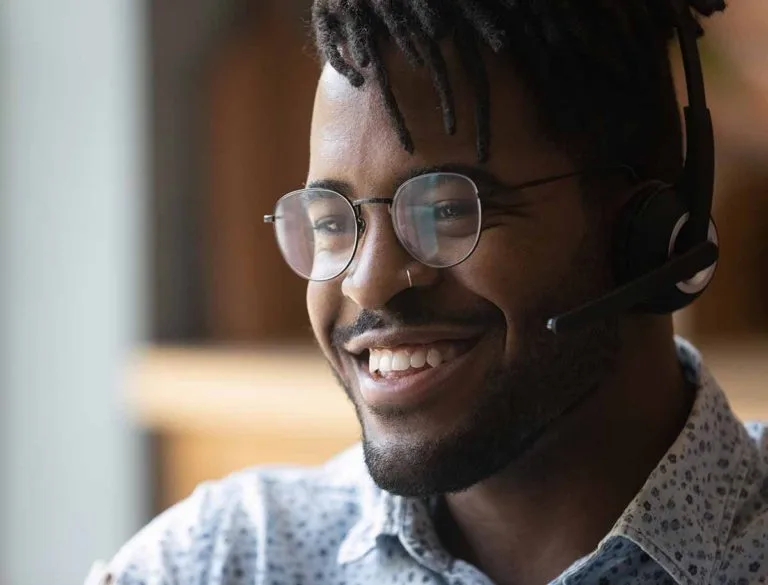 A friendly customer support representative wearing a headset smiles while assisting a client with Online POS and Merchant Services.
