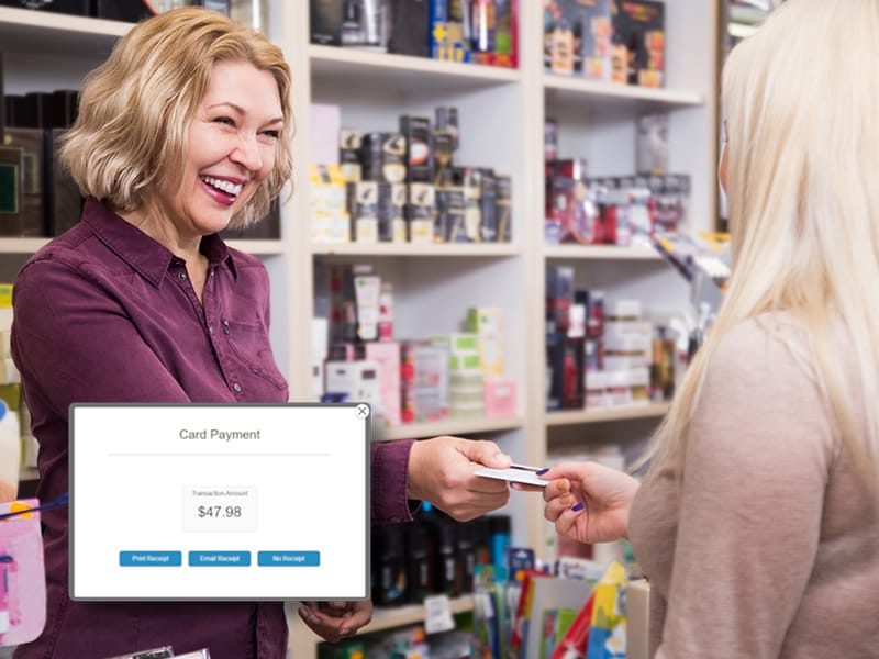 A smiling beauty store cashier processes a customer’s card payment using a Beauty Supply POS System, highlighting a seamless checkout experience.